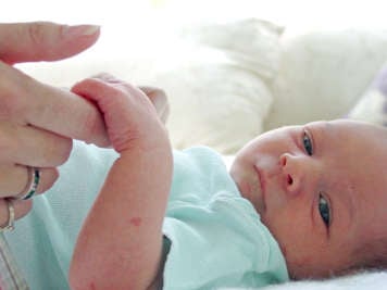 Bébé qui tient le doigt de sa mère